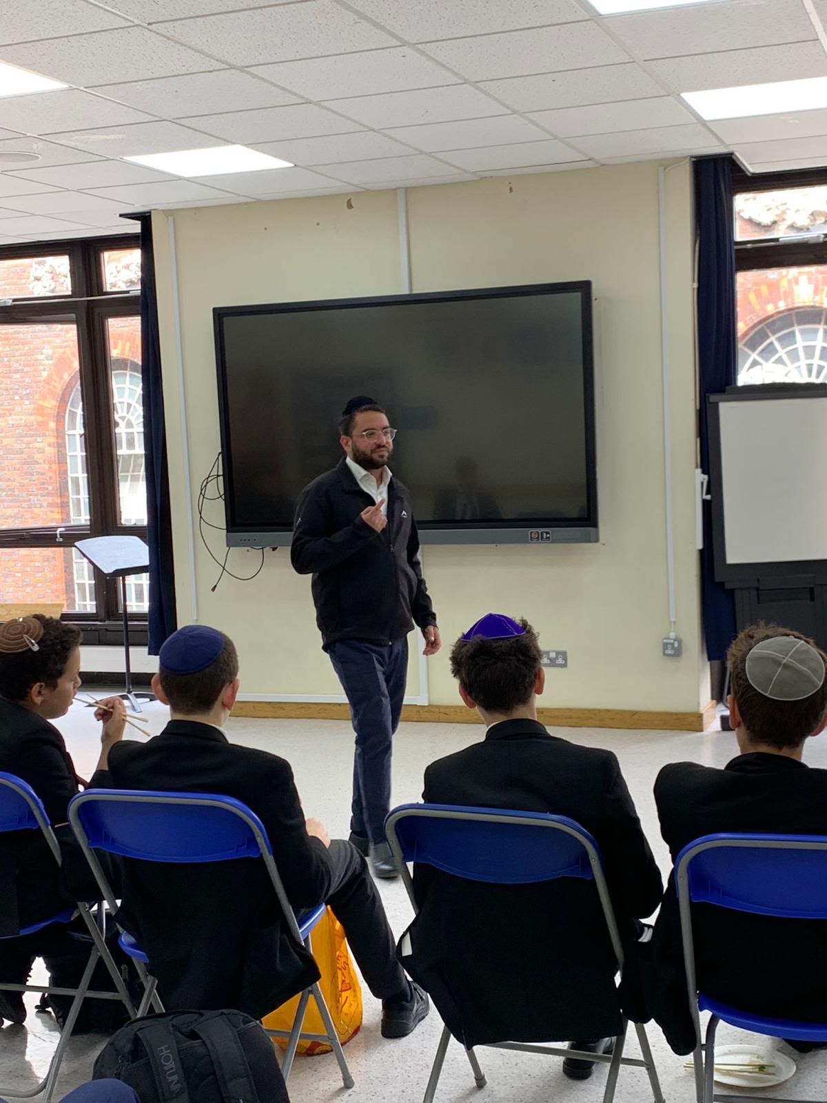 Rabbi Aidyn teaching at the front of a classroom